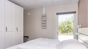 A bedroom with a bed, a chair, a wardrobe, and a view of the outdoors. - 5 Star Holiday Home in Oster Assels (Øster Assels)