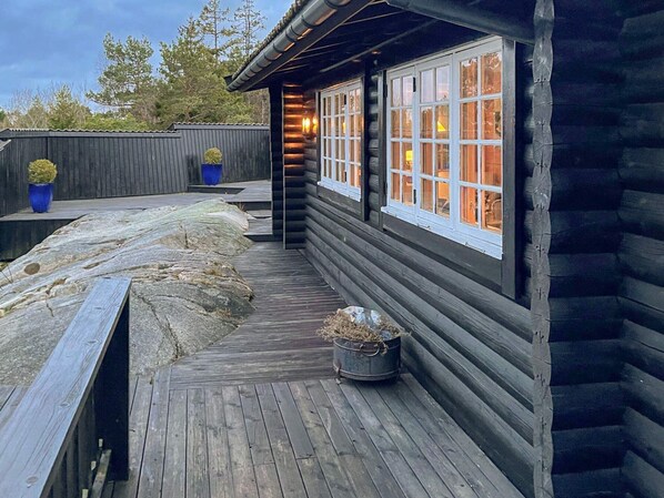 A wooden deck with a stone pathway, a metal bucket, and a blue potted plant.