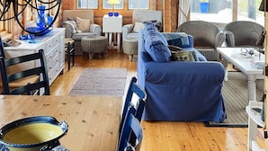 A cozy cabin interior with a dining area, a sofa, and a table with a blue tablecloth. - 10 Person Holiday Home in Skjaerhalden (Hvaler)