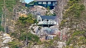 A house built on a rocky hillside with a white exterior and a balcony. - 10 Person Holiday Home in Skjaerhalden (Hvaler)