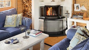A cozy living room with a fireplace, blue sofas, and a white coffee table with books and a glass. - 10 Person Holiday Home in Skjaerhalden (Hvaler)