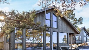 A modern wooden cabin with large windows and a deck.