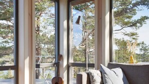 A room with a grey sofa, a guitar, and a vase on a wooden table.
