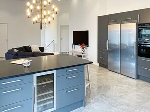 A modern kitchen with a central island, built-in appliances, and a chandelier. - 5 Star Holiday Home in Vastervik (Vastervik)