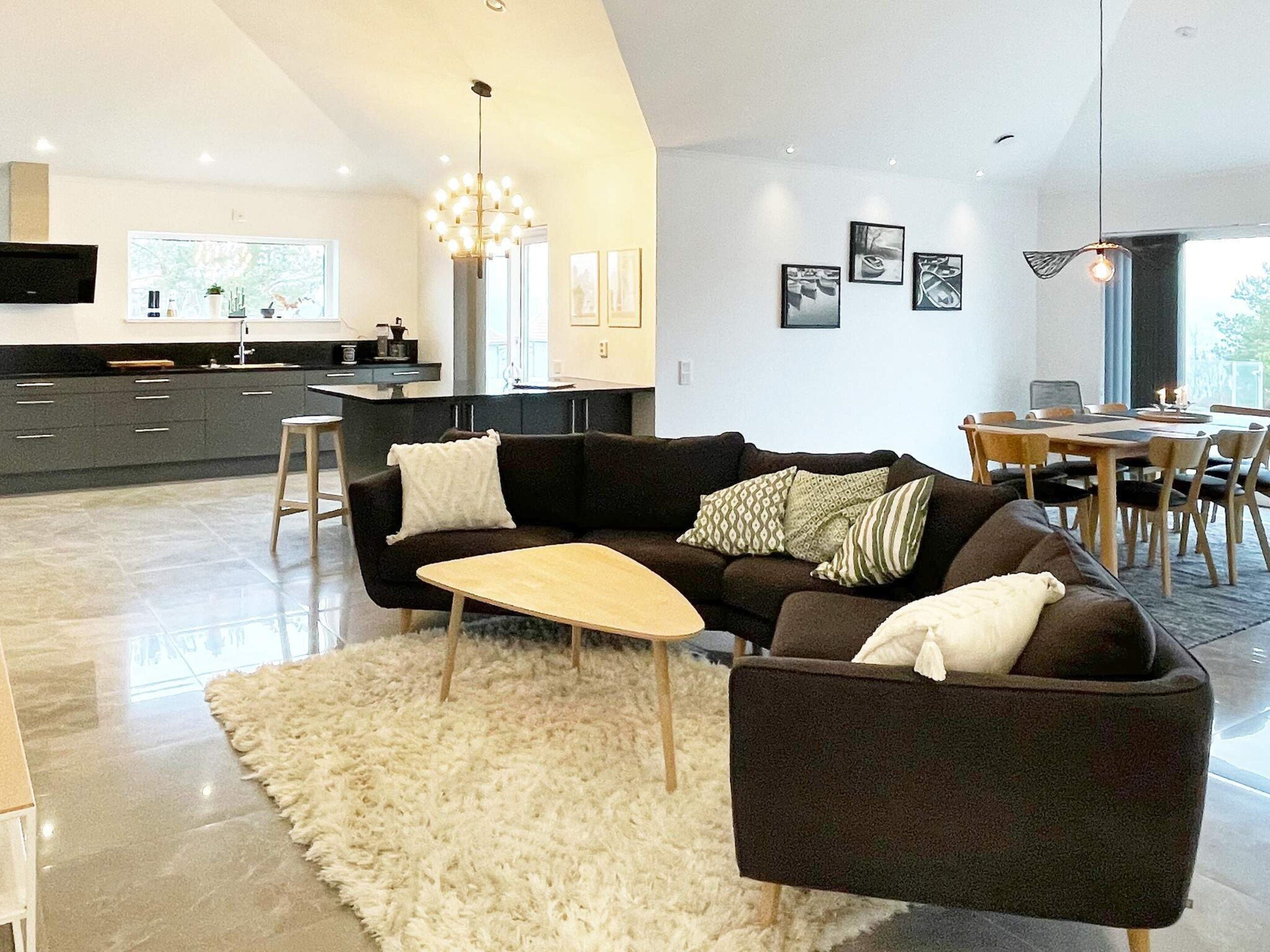 A modern living room with a dark sofa, a small wooden coffee table, and a fluffy rug.