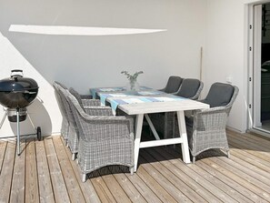 Una terrazza con tavolo e sedie, un barbecue e una porta a vetri scorrevoli.