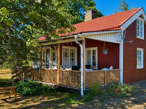 Et træhus med rødt tag, en veranda og skorsten.
