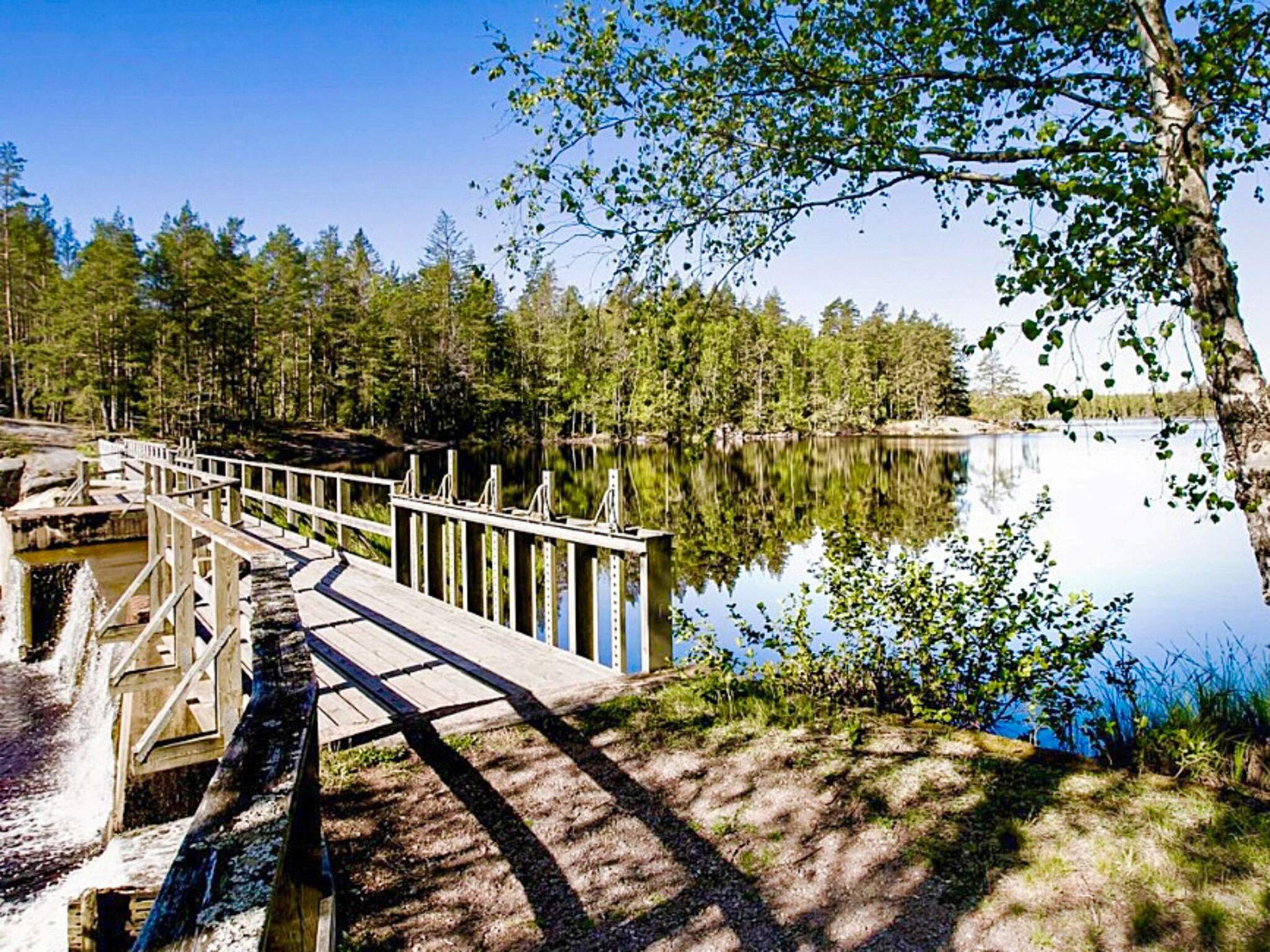 A wooden dock extending into a calm lake surrounded by dense trees.
