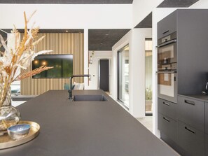 A modern kitchen with a central island, built-in appliances, and a view to the outdoors. - 5 Star Holiday Home in Ansager (Ansager)
