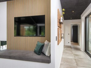 Interior moderno com área de estar integrada, uma grande janela e um corredor que leva a outro quarto.