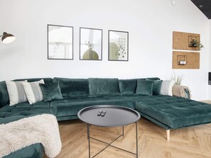 A modern living room with a sectional sofa, a round coffee table, and framed artwork on the wall. - 5 Star Holiday Home in Ansager (Ansager)
