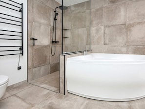 Une salle de bain moderne avec une baignoire sur pieds, une douche à parois de verre et un porte-serviettes.