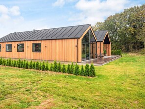 A modern wooden building with a large glass entrance and a deck area. - 5 Star Holiday Home in Ansager (Ansager)