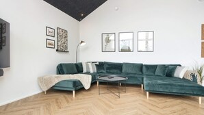 A modern living room with a green sectional sofa, a round coffee table, and a herringbone wood floor. - 5 Star Holiday Home in Ansager (Ansager)