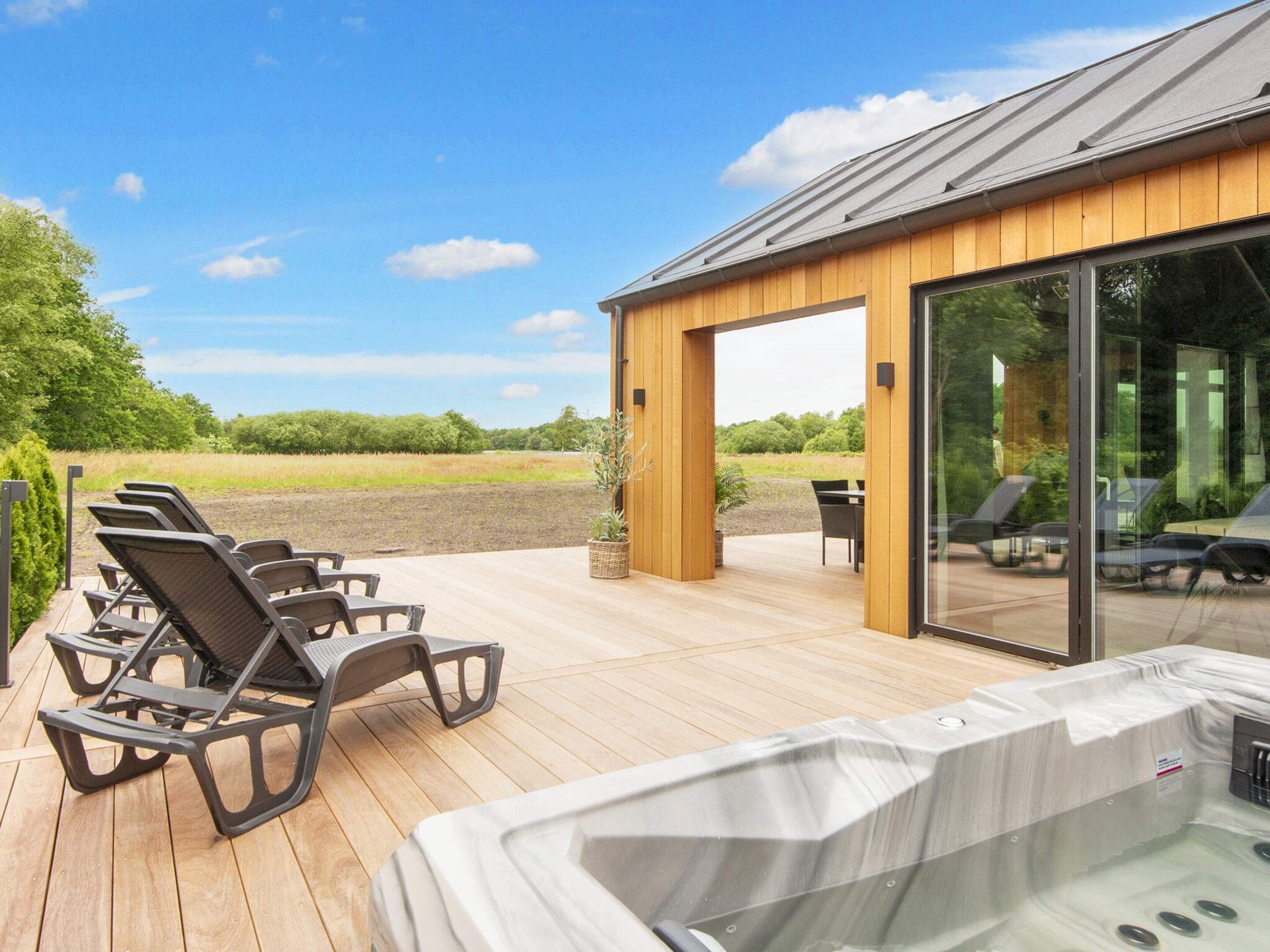 A wooden deck with lounge chairs and a hot tub.