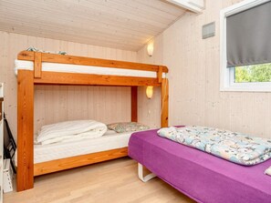 A bunk bed room with a wooden ceiling and walls, a window with a blind, and a purple bedspread. - 6 Person Holiday Home in Roslev (Roslev)