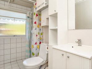 A bathroom with a toilet, a sink, a mirror, and a shower curtain with a fish pattern. - 6 Person Holiday Home in Roslev (Roslev)