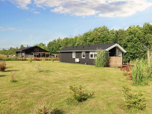 A residential area with two houses, a grassy lawn, and a forested background. - 4 Star Holiday Home in Vaeggerlose (Vaeggerlose)