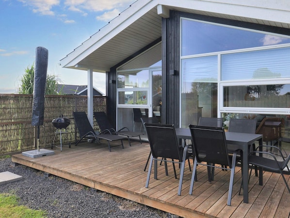 An outdoor patio with a wooden deck, a barbecue grill, and outdoor furniture. - 4 Star Holiday Home in Vaeggerlose (Vaeggerlose)