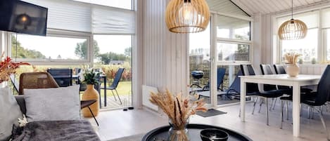 Een moderne woonkamer met een bank, een salontafel en een eethoek met stoelen en een tafel.