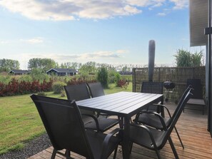 An outdoor patio with a table and chairs, a grill, and a view of the surrounding area. - 4 Star Holiday Home in Vaeggerlose (Vaeggerlose)