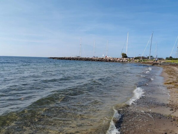 A coastal scene with a rocky breakwater, calm sea, and clear skies. - 4 Star Holiday Home in Vaeggerlose (Vaeggerlose)