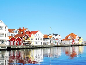 A waterfront with colorful buildings, a calm water body reflecting the structures, and a clear sky.