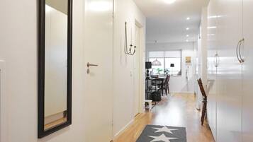 A hallway with a mirror, a star-patterned rug, and a dining area in the background.