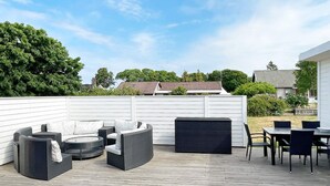 An outdoor patio with wicker furniture, a dining table, and chairs. - 4 Star Holiday Home in Kopingsvik (Kopingsvik)