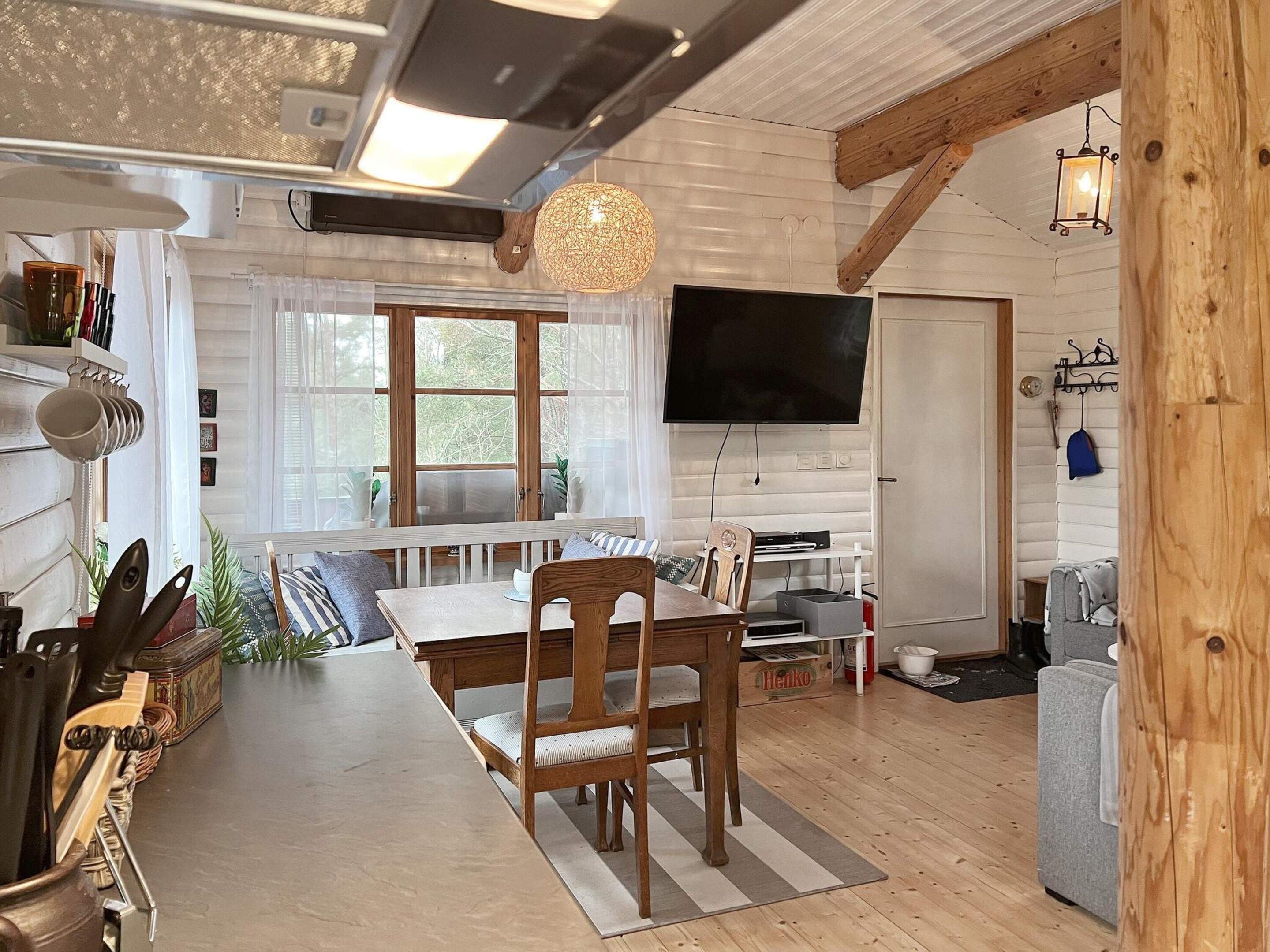 Un salon chaleureux avec une table à manger en bois, des chaises, un téléviseur et une cheminée.