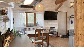Een gezellige woonkamer met een houten eettafel, stoelen, een televisie en een open haard.
