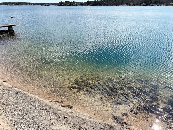A clear lake with a pebble beach and a wooden dock. - 4 Person Holiday Home in Nynashamn (Nynashamn)