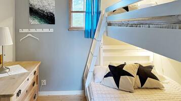 A bunk bed room with a desk, a hanging light, a window with curtains, and a wall-mounted coat rack.