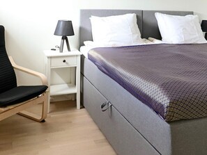 A bedroom with a bed, a nightstand with a lamp, and a chair. - 4 Person Holiday Home in Falkenberg (Falkenberg)