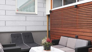A patio area with a sofa, two chairs, and a table with a white tablecloth. - 4 Person Holiday Home in Falkenberg (Falkenberg)