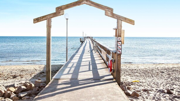 A wooden pier leading to a beach with a lifebuoy and no visible amenities. - 4 Person Holiday Home in Falkenberg (Falkenberg)