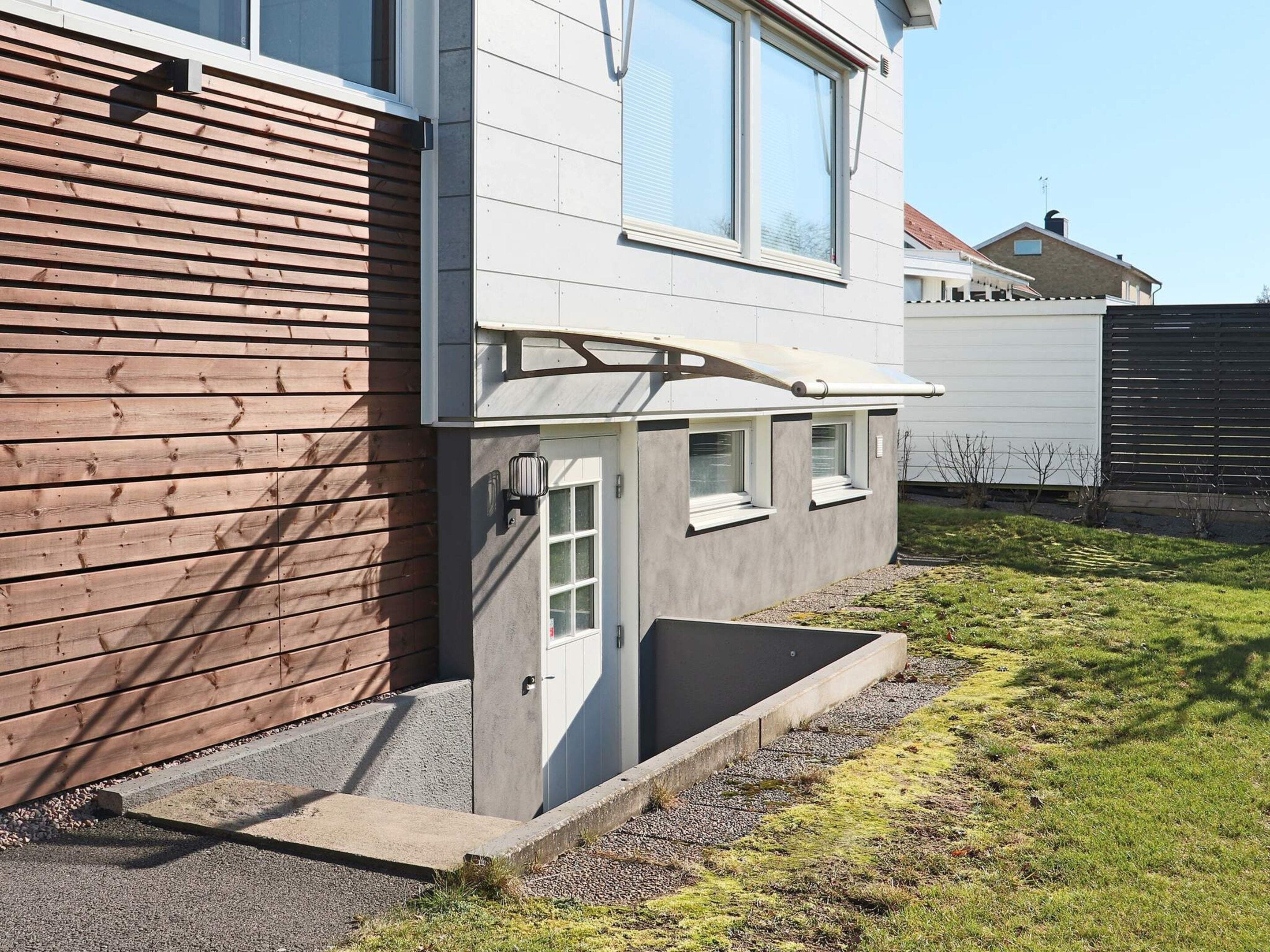 A residential building with a sloped roof, a small porch, and a concrete planter.