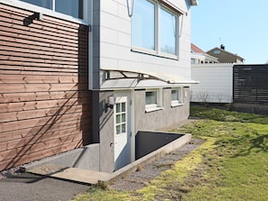 A residential building with a sloped roof, a small porch, and a concrete planter. - 4 Person Holiday Home in Falkenberg (Falkenberg)