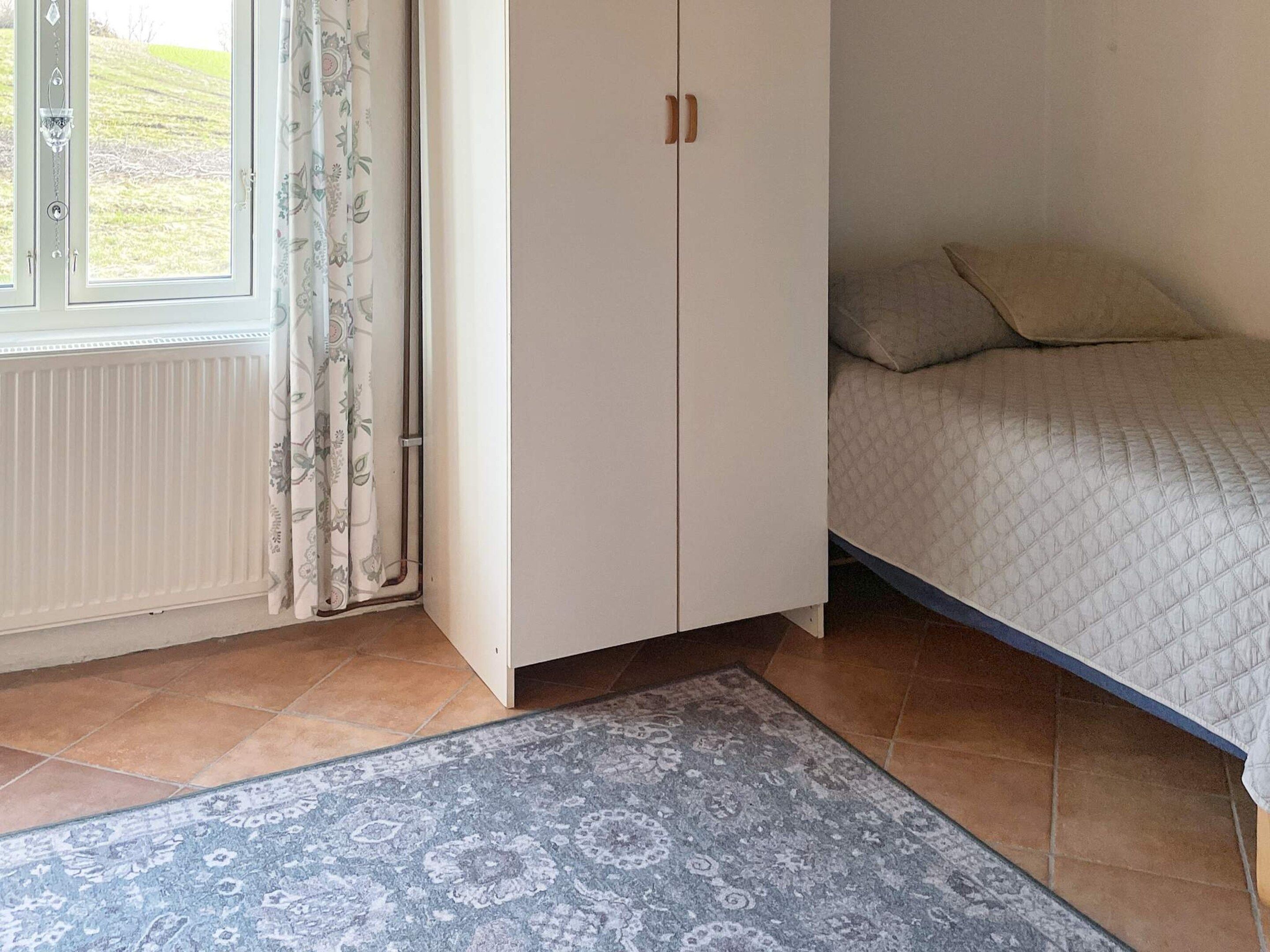 Ein Schlafzimmer mit einem Bett, einem Kleiderschrank, einem Heizkörper und einem gemusterten Teppich.