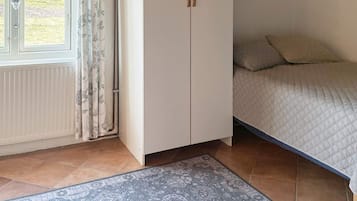 A bedroom with a bed, a wardrobe, a radiator, and a patterned rug.