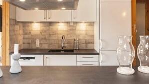 A modern kitchen with a stainless steel range hood, a sink with a faucet, and a white refrigerator. - 6 Person Holiday Home in Hadsund (Hadsund)