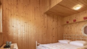 A wooden-paneled room with a bed, a bedside table, and a wall-mounted mirror. - 6 Person Holiday Home in Hadsund (Hadsund)