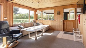 A wooden interior with a sofa, table, and a television mounted on the wall. - 6 Person Holiday Home in Hadsund (Hadsund)