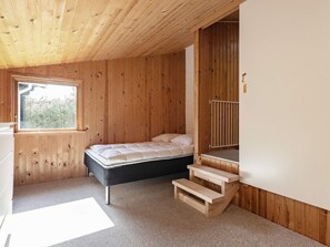 A room with a bed, a window, a radiator, and a wooden staircase. - 6 Person Holiday Home in Hadsund (Hadsund)
