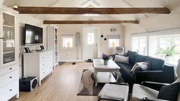 A spacious living area with a ceiling fan, a television, a sofa, a coffee table, and a dining table.