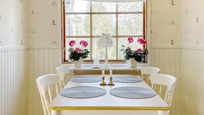 Une table à manger avec des sets de table, deux vases ornés de fleurs et une lampe blanche.