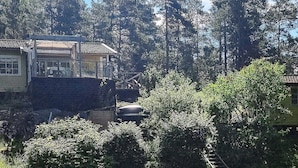 Un quartier résidentiel où se trouve une maison dotée d’un balcon, entourée d’une végétation luxuriante et d’arbres imposants.