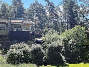 Zona residencial amb una casa que té un balcó, envoltada de vegetació abundant i arbres alts.