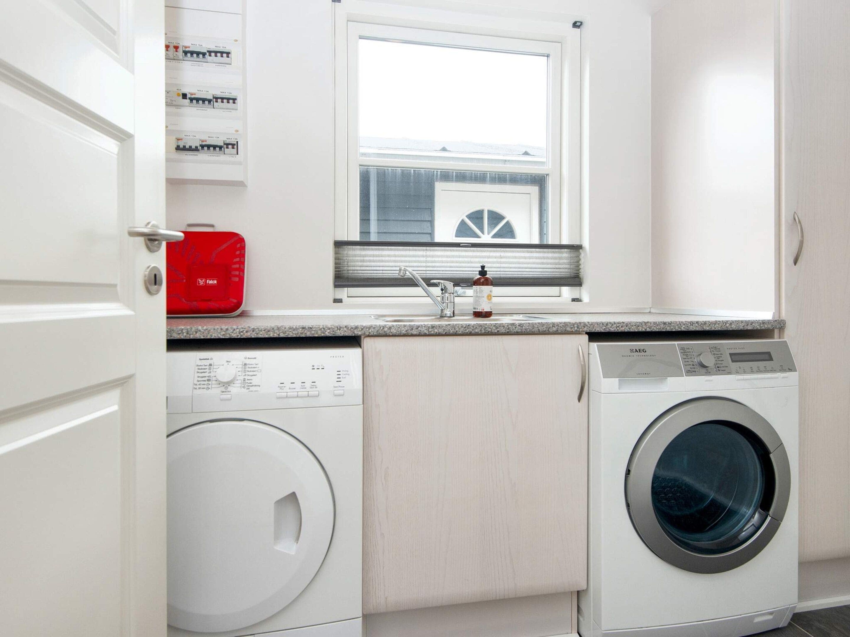 A laundry room with a washing machine, dryer, and a window above a sink.
