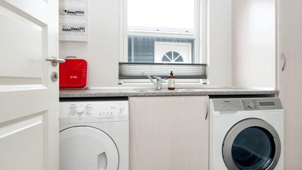 A laundry room with a washing machine, dryer, and a window above a sink.
